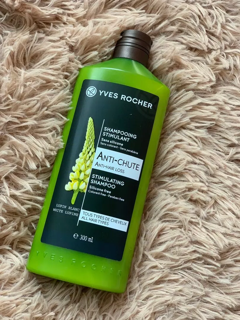 Dầu gội giảm rụng tóc Yves Rocher Anti Hair Loss Stimulating Shampoo có bao bì màu xanh lá cây, tem dán mặt trước in hình một nhành hoa Lupine trắng đẹp tinh tế, nổi bật (ảnh: internet).