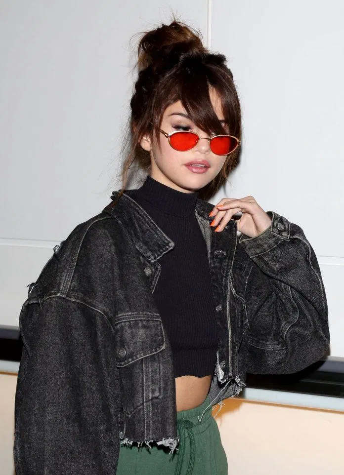 Giọng ca "Love you like a love song" năm nào, chất lừ với áo khoác denim croptop đen, kính râm màu đỏ và tóc búi cao cực sành điệu. (nguồn ảnh: Internet)