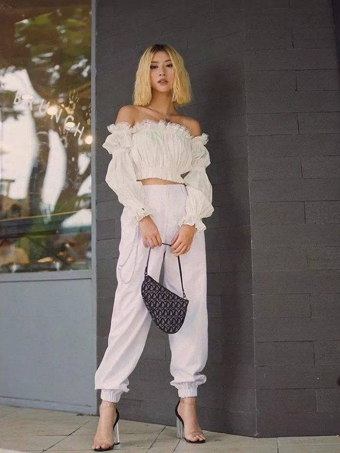 Quỳnh Anh Shyn chơi hẳn "cây trắng" sành điệu với áo trễ vai croptop nhún tay bèo với quần Jogger trắng. (nguồn ảnh: Internet)