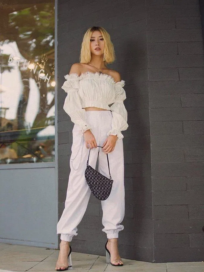 Quỳnh Anh Shyn chơi hẳn "cây trắng" sành điệu với áo trễ vai croptop nhún tay bèo với quần Jogger trắng. (nguồn ảnh: Internet)