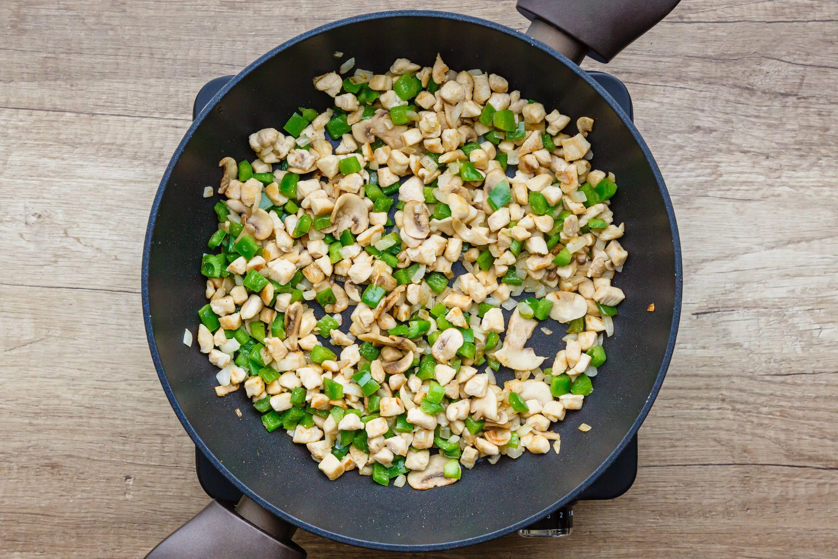 Thêm hành tây, nấm và ớt chuông xanh vào chảo xào (Nguồn: The Spruce Eats)