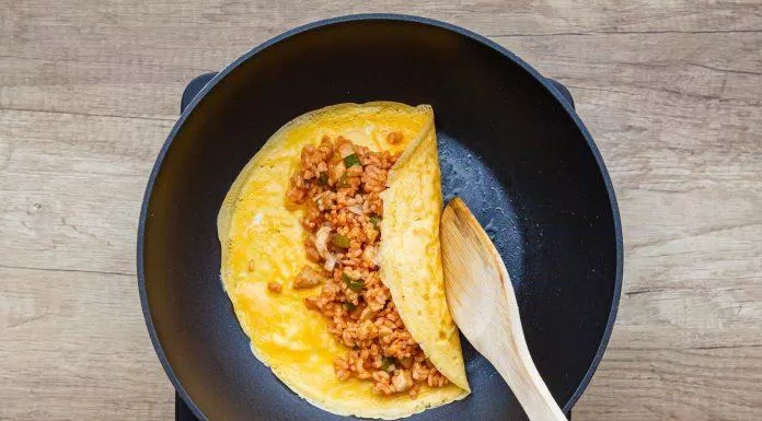 Múc cơm để vào giữa trứng và tiến hành cuộn trứng ( Nguồn: The Spruce Eats)