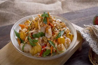 Trình bày gỏi gà chôm chôm ra đĩa và thưởng thức kèm với bánh đa hoặc phồng tôm (Nguồn: Bếp Cô Minh)