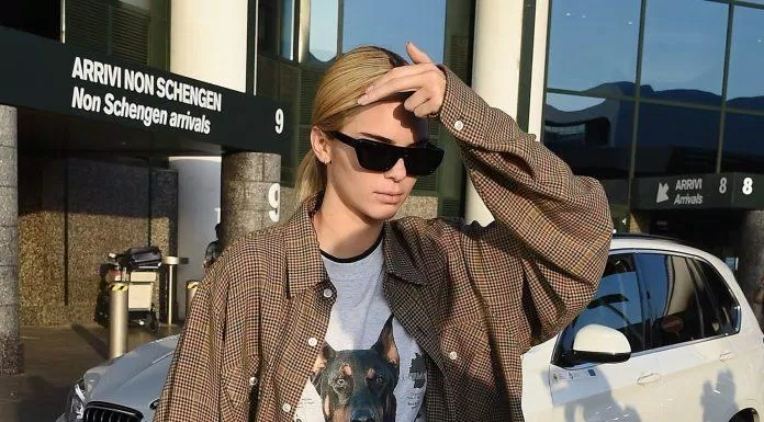 Nàng thơ Kendall Jenner cũng góp mặt trong chiếc áo sơ mi sọc nâu và áo thun trắng in slogan huyền thoại. (nguồn ảnh: Internet)