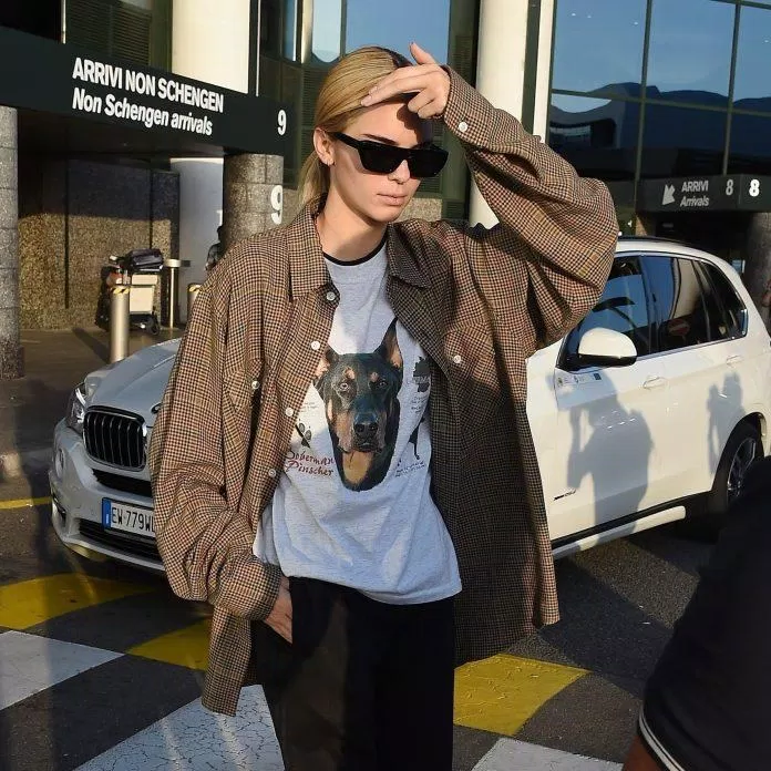 Nàng thơ Kendall Jenner cũng góp mặt trong chiếc áo sơ mi sọc nâu và áo thun trắng in slogan huyền thoại. (nguồn ảnh: Internet)