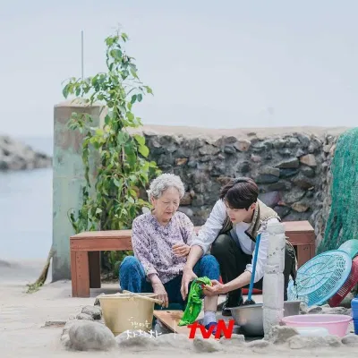 Dân làng Gongjin trong đêm nhạc hội (Nguồn: TvN) Tổ trưởng Hong giúp bà giặt đồ (Nguồn: TvN)