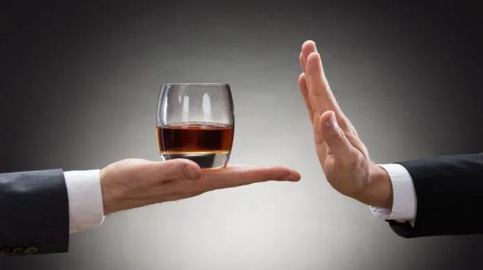 Rượu không tốt cho sự phục hồi cơ thể sau tập luyện (Ảnh: Internet). Close-up Of Businessman Hand Reject A Glass Of Whisky Offered By Businessperson