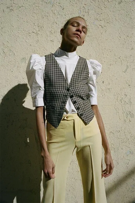 Chiếc áo sơ mi có phần tay phồng tưởng chừng khó kết hợp lại đi kèm với một em gile vest caro đen trắng cực “nuột”. (Nguồn: Internet).