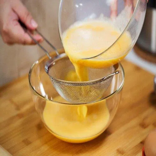 Hỗn hợp sữa nóng và lòng đỏ trứng gà được lọc qua rây để mịn hơn. (Nguồn: Internet)